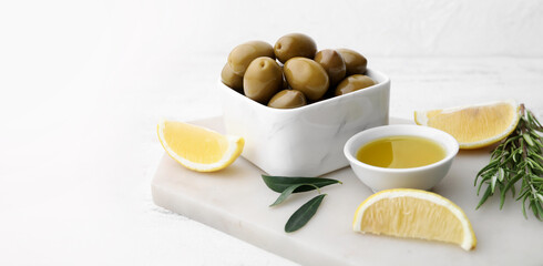 Green olives, oil and lemon slices on white table