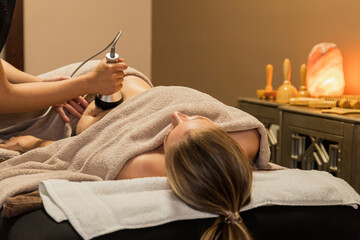 A woman lying on a spa bed receiving a laser cavitation massage