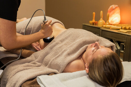 Woman lying down receiving a laser cavitation massage