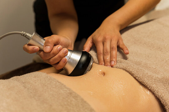 Woman receiving cavitation massage on her belly 