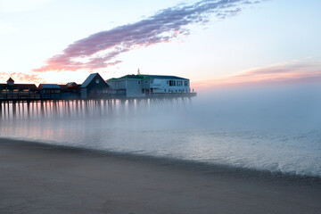 Pier in fog at dawn. A famous place on the coast of the Atlantic Ocean. Old pier. USA. Maine. Old Orchard Beach.
