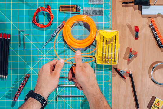 Detail of male hands cutting wires with scalpel.