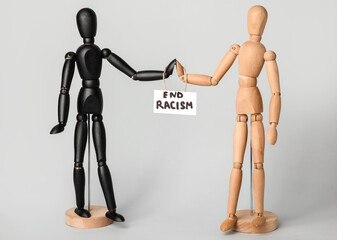 Wooden mannequins and paper sheet with text END RACISM on grey background