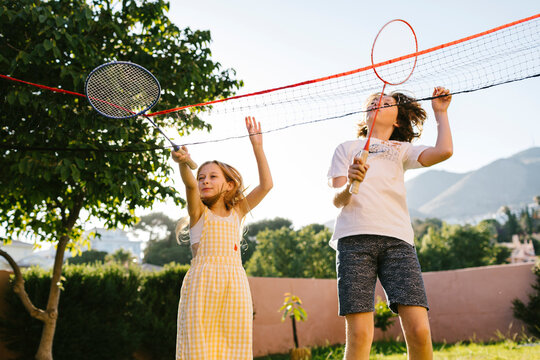Siblings jumping and playing badminton