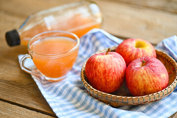 apple cider vinegar natural remedies and cures for common health condition,  raw and unfiltered organic apple cider vinegar in glass with apple fruit on basket on the wooden table