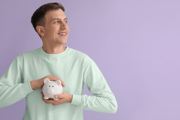 Fototapeta na wymiar Young man with white piggy bank on violet background