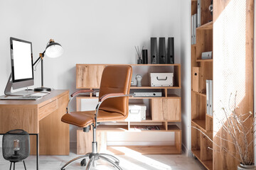 Interior of light office with desk, chair and shelving unit