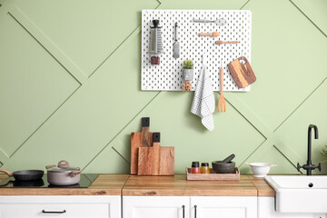 Counters with kitchen utensils near green wall