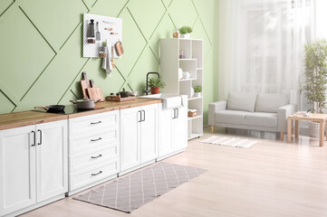 Interior of stylish kitchen with white counters, pegboard and shelving unit