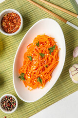 Bowl with delicious carrot salad and ingredients on green mat