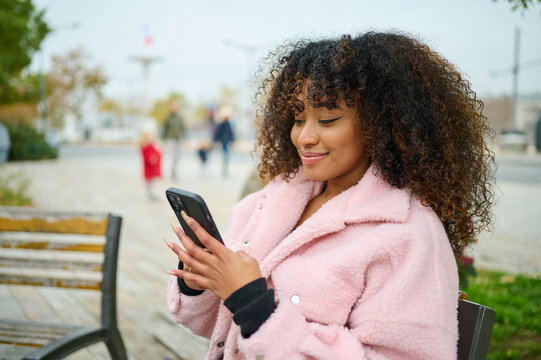 Young curly Woman smiling On The Phone In Winter