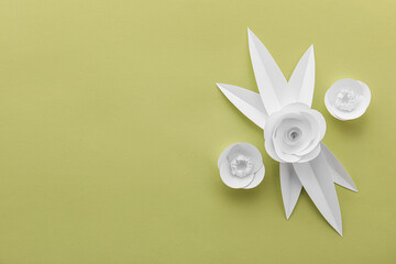 Beautiful origami flowers and leaves on green background