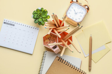 Set of different stationery with alarm clock on color background
