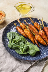 Plate of tasty baked carrots and spinach on light table, closeup
