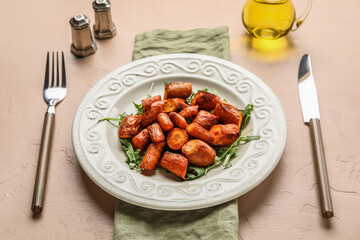 Plate of tasty baked carrots with cutlery on color background