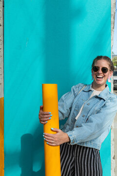 Woman laughing and holding on to a yellow pipe
