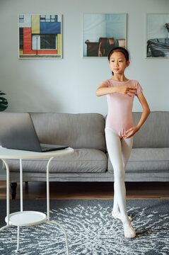 Little girl wearing ballet shoes at home