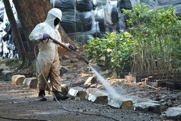 A worker using a hazmat sprays water and flushes the sewers