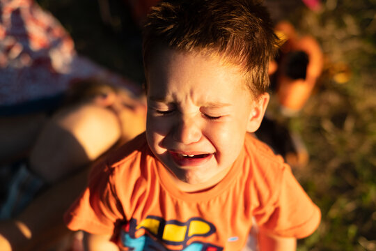 A portrait of a crying toddler taken outdoors