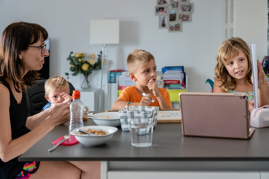 Children doing homework with their mom at home
