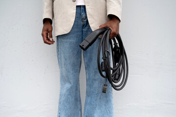 Anonymous black man with electric car cable