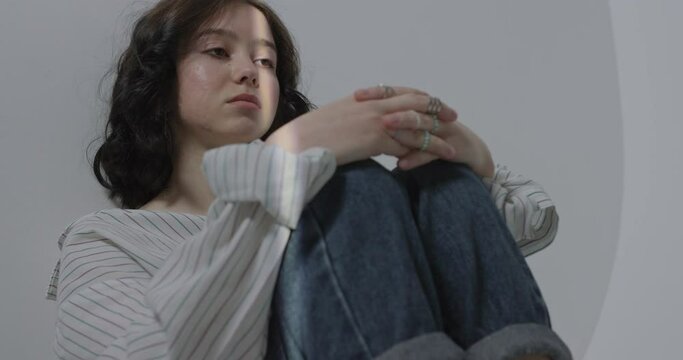 Sad teenager sitting on the floor. Pain of a teenager due to parental quarrels.