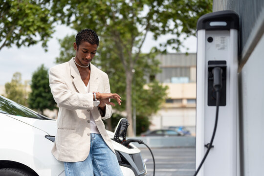 Black man waiting  While Recharging Electric Vehicle