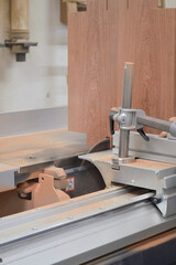 A man cuts wood on a circular saw in a joinery, band saw, holding a plank