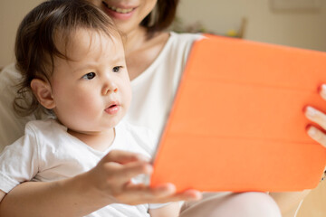 A curious boy watches tablet PC with his mother