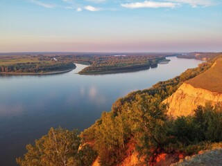 Clay coast with groves of birch trees, soil erosion, sunset clouds and the Ob riverbed