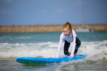 young surfer ride on surfboard with fun on sea waves. Active family lifestyle, kids outdoor water sport lessons and swimming activity in surf camp. Summer vacation with child