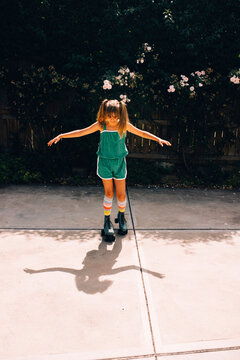 Young girl in green shorts and green roller skates