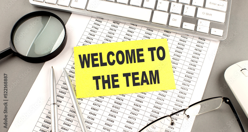 Poster welcome to team text written on a sticky on chart with keyboard and magnifier