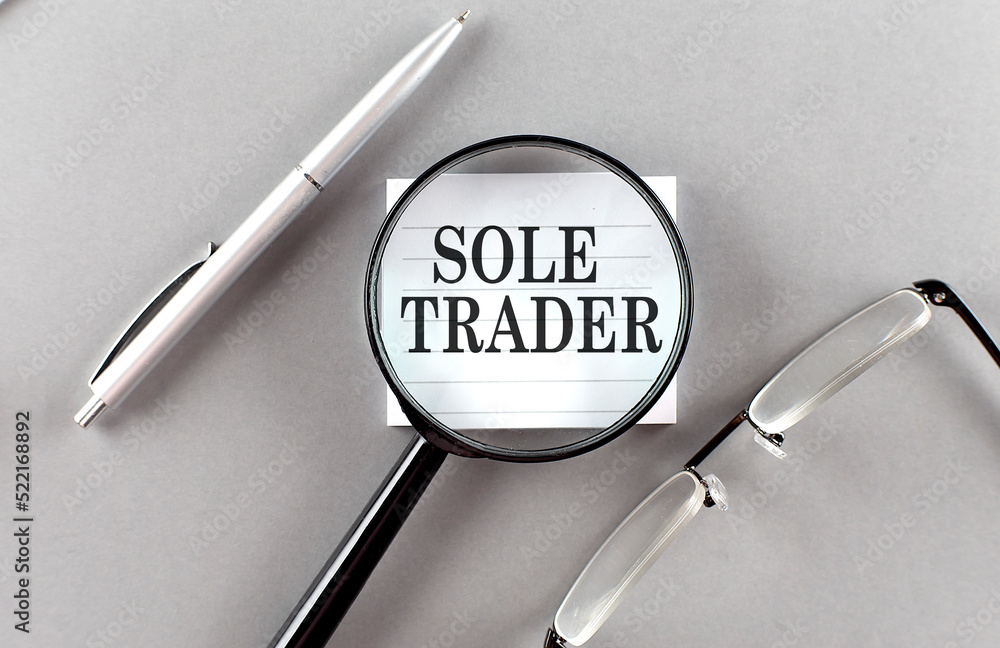 Aufkleber word sole trader on sticky through magnifier on grey background