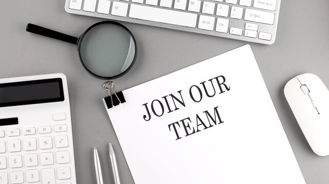 JOIN OUR TEAM written on paper with office tools and keyboard on the grey background