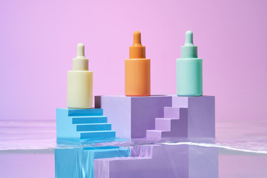Three bottles with serum on color podium in the rippling water