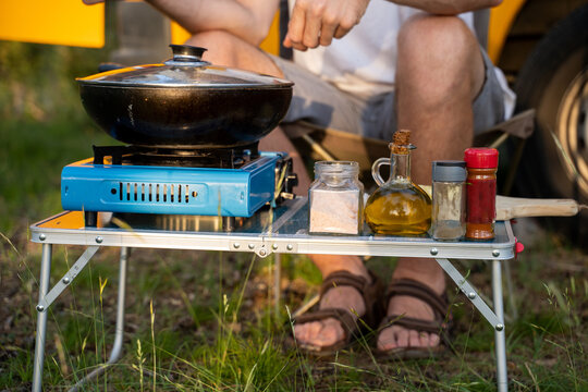 Man camping and cooking with camper van in nature
