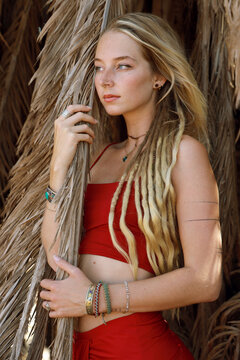 young woman with dreadlocks standing between palm leaves