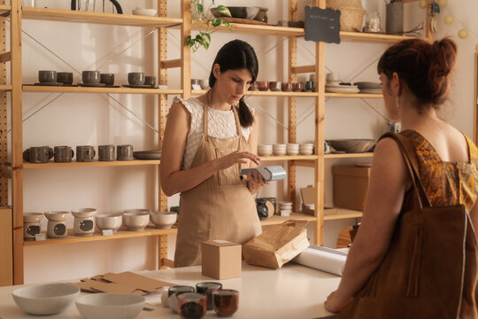 Female Owner Of The Ceramics Shop Serving The Customer