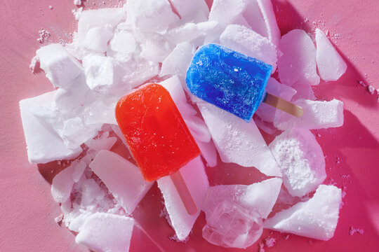 Red and Blue popsicles and crushed ice on pink table