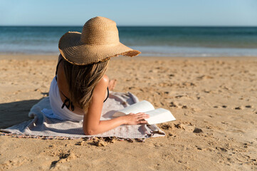 Unrecognizable woman reading book on beach
