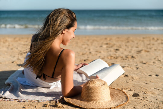 Unrecognizable woman reading book on beach