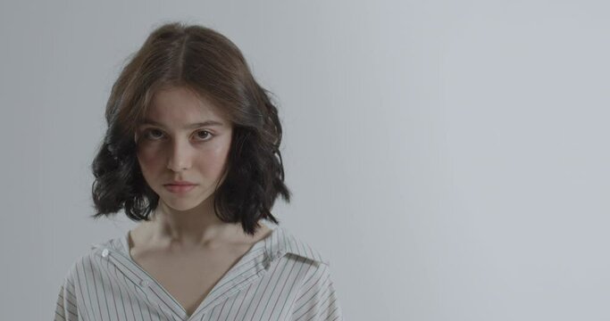 The girl closes her mouth with her hands. Conversation with gestures.