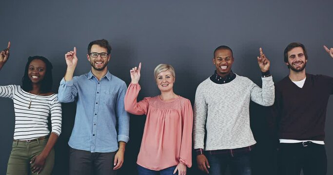 Diverse creative team pointing at promotion, marketing deal and advert against a grey copy space background in studio. Portrait of smiling, happy and excited and group of men and women endorsing sale