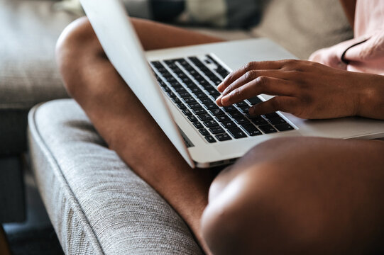 Crop woman using laptop on sofa