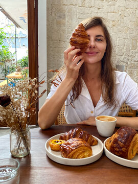 Young woman with a croissant in her hands in a cafe