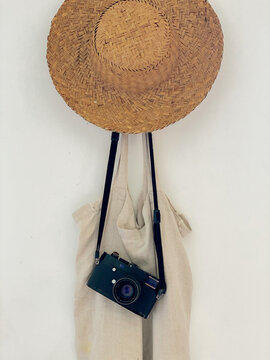 A straw hat, retro camera and a bag hang on a hanger 