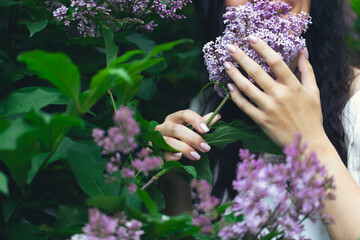 Hands of an attractive woman with a bouquet of lilacs. Spring and summer, seasonal photos. Front view.