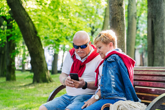 Elderly Couple Surfing Cellphone On Street