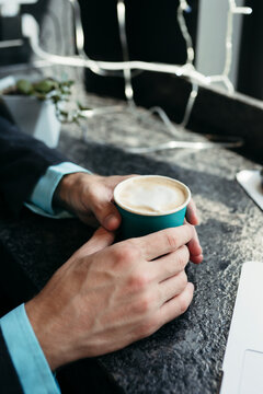 Disposable cup of coffee in hands of faceless man.